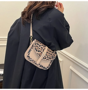 Detail of leopard print crossbody bag with gold buckle on a stylish model in black blazer