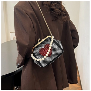 Detail of crossbody bag featuring crystal rhinestones, red heart motif, and pearl handle