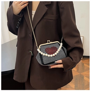 Detail of a sparkling rhinestone heart crossbody bag with elegant pearl handle
