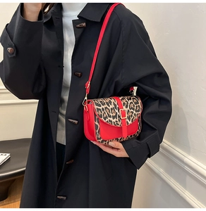 Detail of red crossbody bag with leopard print flap and metal buckle on black coat
