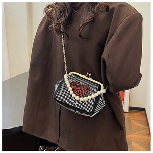 Detail of heart rhinestone evening bag with pearl handle and golden chain strap