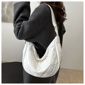 Detail view of white quilted crescent bag showing the rhombic stitching and wide strap