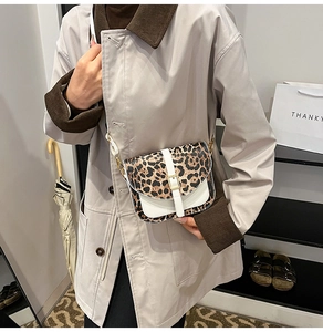 Detail of a mini leopard print saddle bag with white leather trim and gold buckle closure