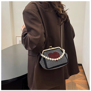 Detail of rhinestone heart crossbody bag with pearl handle worn over a brown blazer