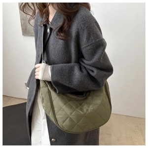 Detail of army green quilted crescent bag showing textured nylon fabric and shoulder strap