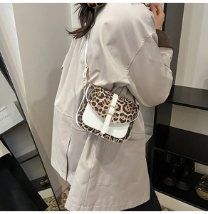 Chic leopard print and white leather crossbody bag shown on a model in a modern interior