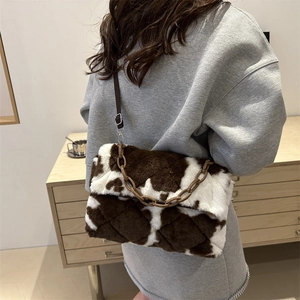 Plush cow print shoulder bag with quilted texture and decorative brown chain strap