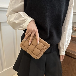 Quilted khaki clutch bag with grid stitching pattern held by a model for daily styling