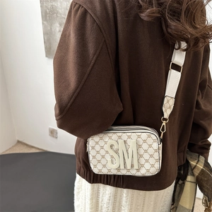 Classic camera bag with monogram print and wide strap shown on a model in profile