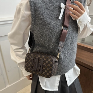 Brown monogram camera bag with wide strap and SM logo, shown on model in studio