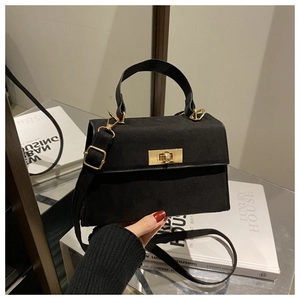 Detail of black suede matte Kelly bag with golden twist lock and adjustable shoulder strap