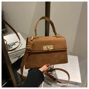 Close-up of brown suede small square bag featuring a gold metal lock and top handle