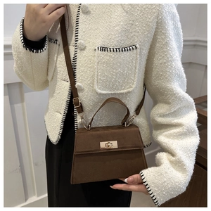 Brown suede crossbody bag with golden twist lock worn by a model in a white coat