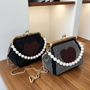 Elegant black fabric handbag with rhinestone heart and pearl handle on wooden desk