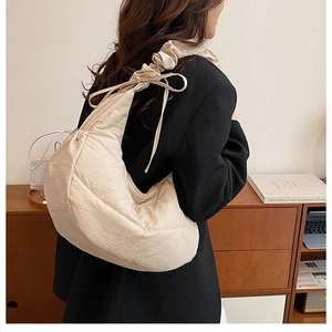 Detalle del bolso de media luna acolchado beige con correa de volantes y lazos decorativos