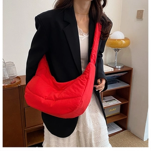 Primer plano de bolsa de media luna de nailon acolchado rojo sobre blazer negro