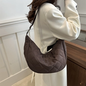 Quilted dark brown hobo bag with moon shape and adjustable strap worn by model