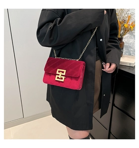 Detail of burgundy velvet crossbody bag with gold buckle and quilted pattern on model