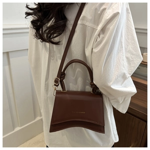Deep brown matte leather crossbody bag with curved base and gold lettering detail