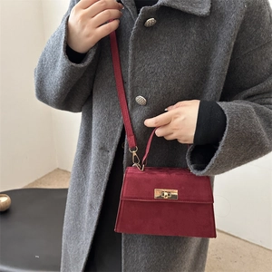 Classic burgundy matte suede handbag with golden buckle worn on a grey winter coat