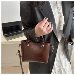 Detail of dark brown leather bucket bag with FASHION embossing and golden hardware