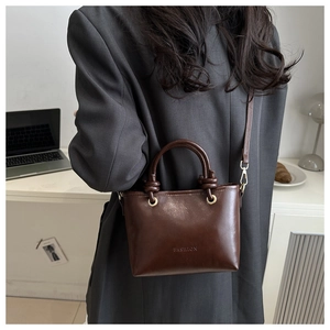 Detail of dark brown leather bucket bag with gold circular handle and fashion embossing