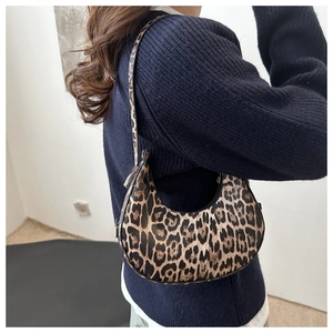 Détail du sac sous le bras en croissant imprimé léopard porté sur un pull en maille