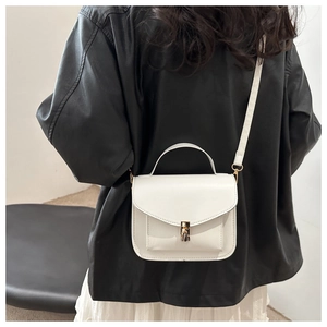White minimalist square crossbody bag with gold lock and top handle shown on model