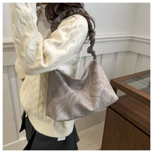 Détail du cabas à motif marbré avec bandoulière froncée porté par un mannequin