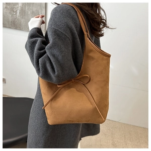 Close-up of brown suede hobo bag featuring a decorative bow on the side of shoulder strap