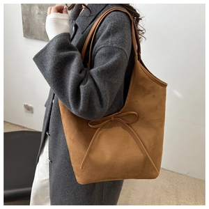 Macro detail of brown frosted suede tote bag with decorative bow and matte texture