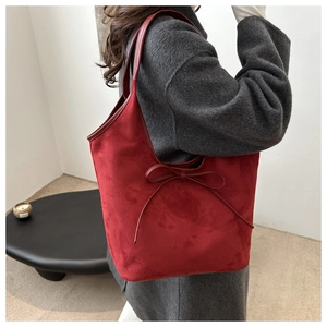 Detail of red frosted bucket bag with leather bow worn with a charcoal wool coat
