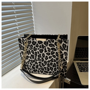 Detail of leopard print tote bag with gold chain and black strap in an office setting