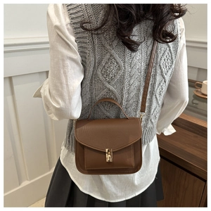 Rear view of brown vintage crossbody bag with gold lock and adjustable strap
