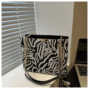 Detail of zebra pattern knit shoulder bag with gold chain strap and metal clasp