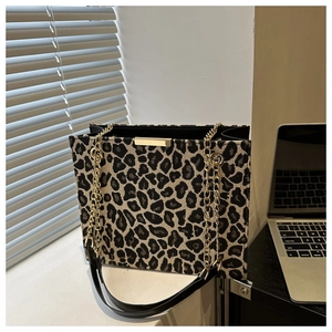 Detailed view of leopard print tote bag with gold chain and black leather strap on desk