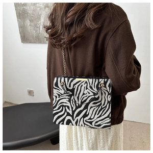 Detail of a chic zebra print shoulder bag with gold metal hardware and chain strap