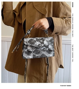 Detail of snake print crossbody bag with knotted handle and elegant V-shaped flap