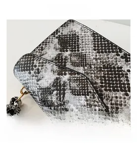 Macro shot of faux snakeskin texture and golden metal ring hardware on the shoulder bag