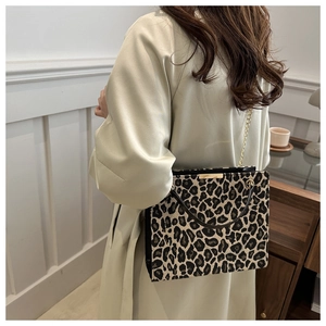 Chic leopard print shoulder bag featuring gold chain strap on a model in a cozy interior