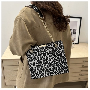 Leopard print crossbody bag with gold chain strap shown in a modern home setting
