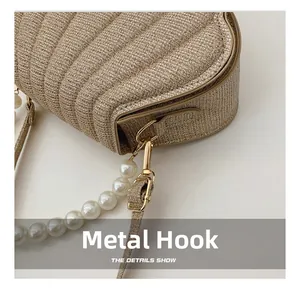 Detailed macro view of the gold felt shell bag featuring a pearl strap and hardware hook