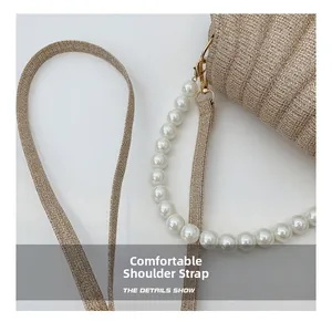 Detail of champagne gold pleated bag showing pearl chain and golden metal hardware