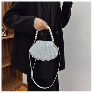 Detail of silver sequined shell bag with pearl handle worn by model in black suit