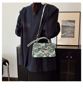 Detail view of green snake print crossbody bag with woven handle and shoulder strap
