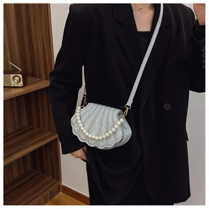 Detail of silver glitter shell bag with large pearl chain and sleek metal hooks