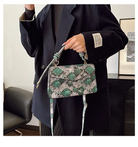 Close-up of green snakeskin leather texture and metallic ring handle on the handbag