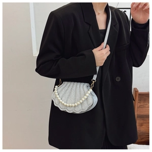 Detail of silver shell-shaped crossbody bag with glitter finish and pearl handle strap