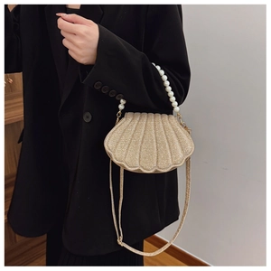 Detail of champagne gold sequined shell bag featuring elegant faux pearl handle and metal strap buckle