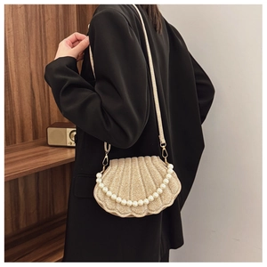 Macro shot of glittery golden shell bag featuring pearl accents and a chain strap